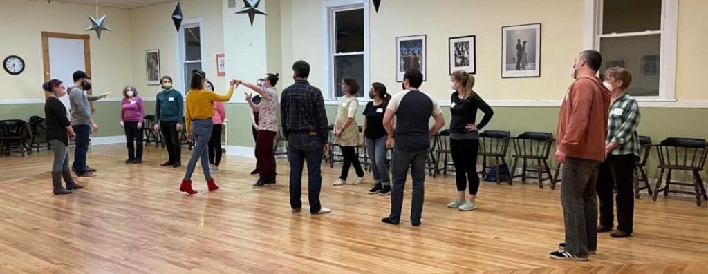 Photo of a West Coast swing dance class. Instructors are demonstrating a right side pass.